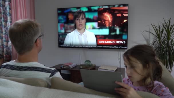 En medelålders man med sin lilla dotter framför en TV-skärm. — Stockvideo