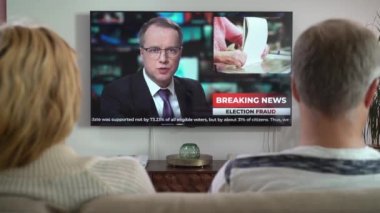 Aile Çifti TV Haberleri İzliyor Kanepede Birlikte Oturuyorlar.