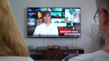 Aile Çifti TV Haberleri İzliyor Kanepede Birlikte Oturuyorlar.