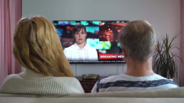 Coppia di famiglie che guarda le notizie TV seduta sul divano in salotto — Video Stock