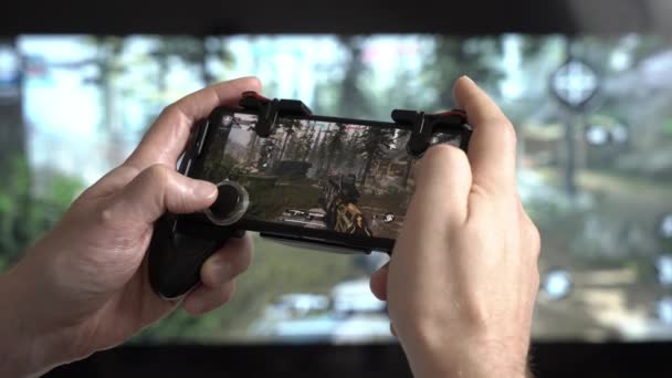 Een man die Call of Duty speelt op een smartphone — Stockvideo