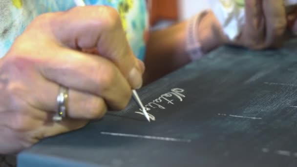 A artista assina sua pintura em sua oficina. — Vídeo de Stock
