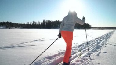 Soğuk ve güneşli bir günde Finlandiya 'da donmuş bir körfezde kayak yapmaya giden bir kadın.