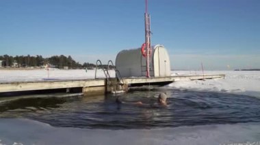 Kışın buz çukurunda yüzen bir adam..