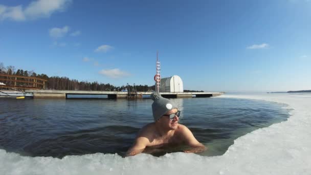 Un homme rêvant de vacances flottant sur un flamant rose gonflable dans un trou de glace — Video