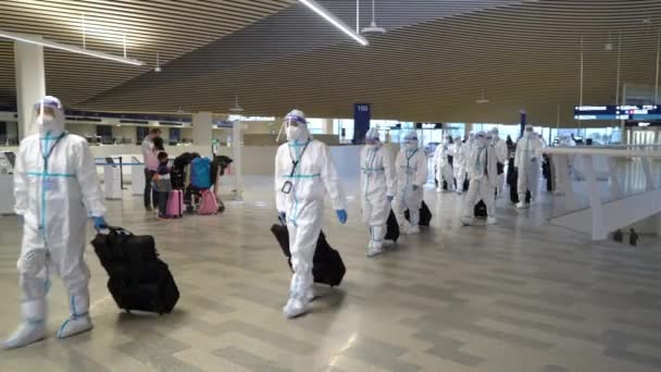 Grupo de turistas asiáticos en trajes antivirus desechables de protección y máscaras en el aeropuerto — Vídeo de stock