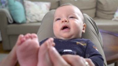 Babasını evde bebeğiyle oynarken görmek. Mutlu baba, çocuğuyla bağ kurup babalık ve çocuk bakımı yapmaktan zevk alıyor. Babasının kucağında yatan tatlı bir bebek. Bebek ayaklar babanın ellerinde. Mutlu