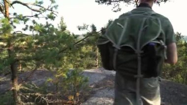 Finlandiya 'da dağ ormanlarında yürüyüş ekipmanlarıyla gezen olgun bir adam ve eski model bir kamerayla nefes kesici kuzey manzaralarını fotoğraflıyor.