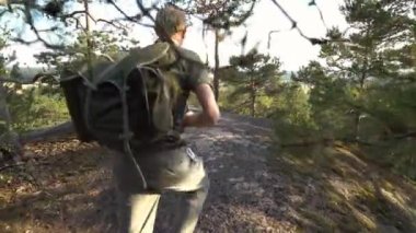 Finlandiya 'da dağ ormanlarında yürüyüş ekipmanlarıyla gezen olgun bir adam ve eski model bir kamerayla nefes kesici kuzey manzaralarını fotoğraflıyor.