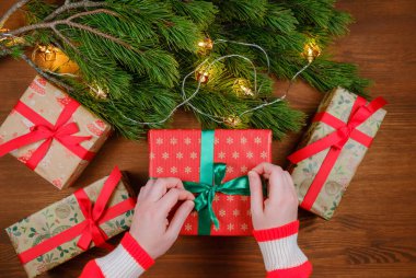 Ahşap arka planda Noel hediyesi paketleyen eller