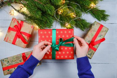 Noel hediyesi olarak beyaz ahşap arka planda Noel ağacı dalları ve xmas ışıkları var.