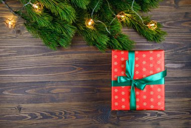 Noel ağacı dalları ve ışıkları olan ahşap arka planda noel hediyesi kutusu. Xmas ve Mutlu Yıllar teması. Düz yerde, üst tarafta. Boşluğu kopyala