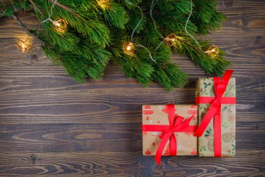 Noel ağacı dalları ve ışıkları olan ahşap arka planda Noel hediyesi kutuları. Xmas ve Mutlu Yıllar teması. Düz yerde, üst tarafta. Boşluğu kopyala