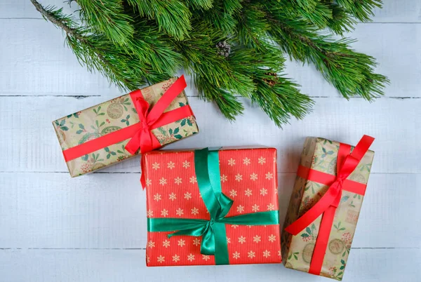 Noel ağacı dallı beyaz ahşap arka planda Noel hediyesi kutuları. Xmas ve Mutlu Yıllar teması. Düz yatış, üst görünüm