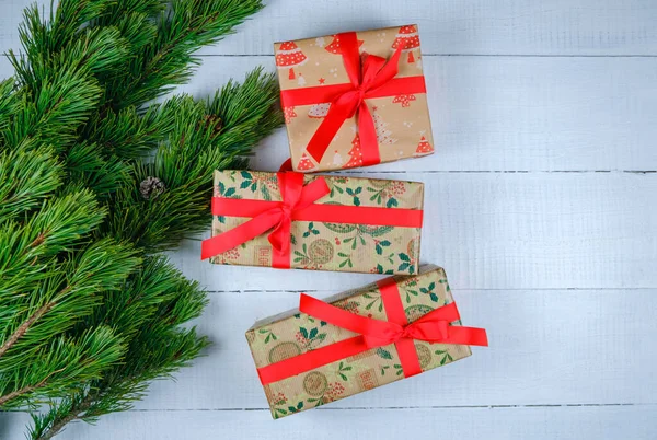 Noel ağacı dallı beyaz ahşap arka planda Noel hediyesi kutuları. Xmas ve Mutlu Yıllar teması. Düz yerde, üst tarafta. Boşluğu kopyala