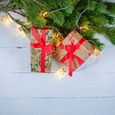 Noel hediyesi kutuları beyaz ahşap arka planda Noel ağacı dalları ve ışıkları var. Xmas ve Mutlu Yıllar teması. Düz yerde, üst tarafta. Boşluğu kopyala