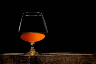 Siyah zemin üzerinde tahta kutu olan bir bardak viski.