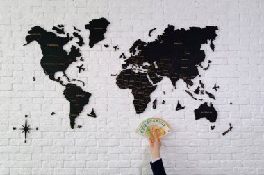 Arka planda dünya haritası olan el ele tutuşan para.