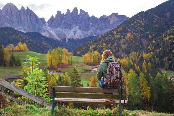 Arka planda Dolomites dağları olan bankta oturan kız, Santa Maddalena köyü, Val di Funes vadisi, Trentino Alto Adige bölgesi, İtalya, Avrupa