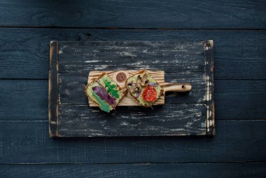 Izgara domatesli avokado tostu, ızgara mantar ve koyu ahşap masada salata. Sağlıklı yiyecekler ve vejetaryen diyet kavramları