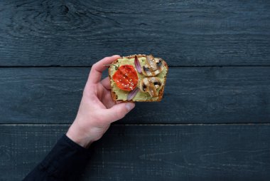 Avokado tostu, ızgara mantar ve ahşap bir masada ızgara domates. Sağlıklı yiyecekler ve vejetaryen diyet kavramları