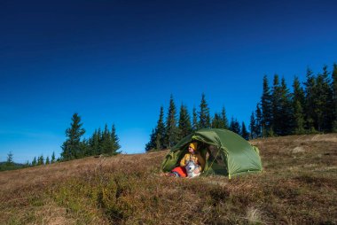 Kamp çadırında genç ve güzel bir kadın Sibirya Husky 'sine sarılıyor. İnsan ve hayvan dostluğu.