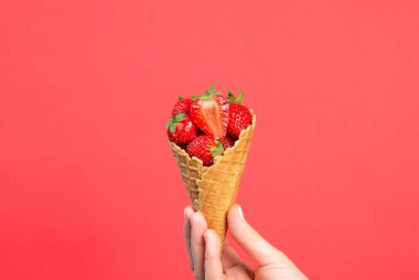 Kırmızı arka planda taze çilekli waffle fincanı.