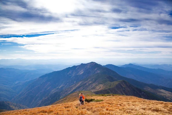 Young beautiful woman in mountains with blue sky and clouds on background