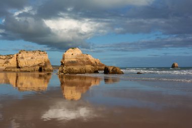 Portekiz, Portimao 'daki Praia dos Tres Castelos. Kireçtaşı kayaları gelgit sularını yansıtır.