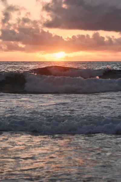 Önünde büyük dalgalarla okyanusun arkasında batan güneş.