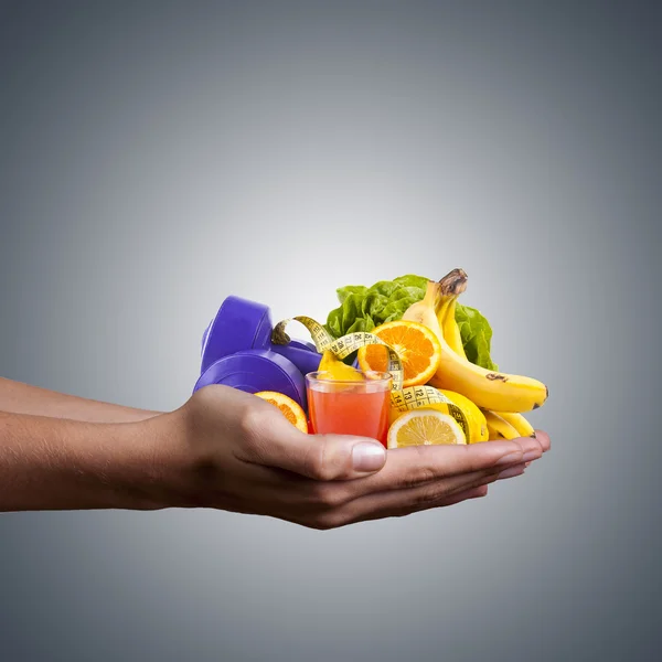 hands with healthy, natural foods, juice and weights for exercise