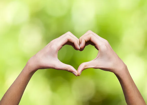 Clasped hands forming a heart with natural background — Stock Photo, Image