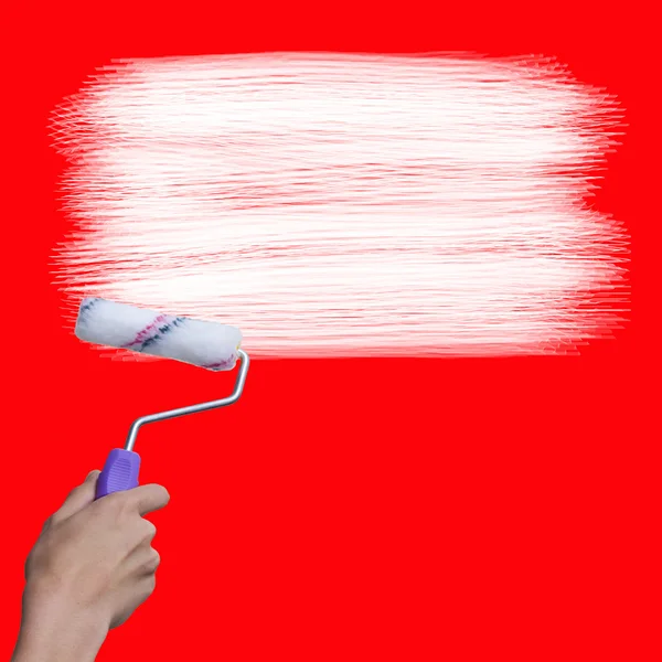 Hand with brush painting in white on red wall — Stock Photo, Image