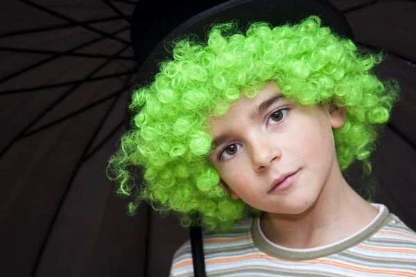 Portret chłopca z zielony parasol perukę i patrząc na kamery — Zdjęcie stockowe