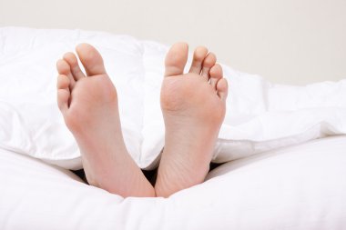 ayakları kapalı yatakta ön planda