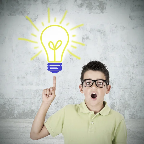 Young caucasian boy pointing foreground lit lightbulb — Stock Photo, Image