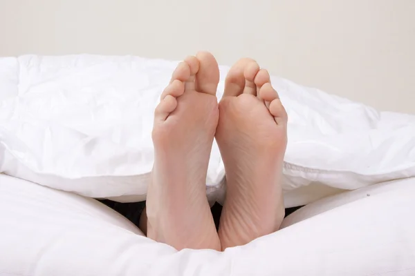 Feet in the foreground in the covered bed — Stock Photo, Image