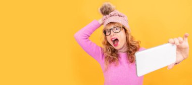 Cep telefonu olan bir kadının portresi izole edilmiş, kış şapkasıyla fotoğraf çekiyor.