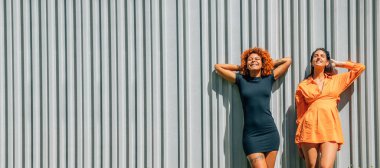 Kızlar sokak duvarında güneşleniyor.