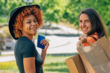 Alışveriş torbaları ve sokakta cep telefonu olan arkadaşlar.