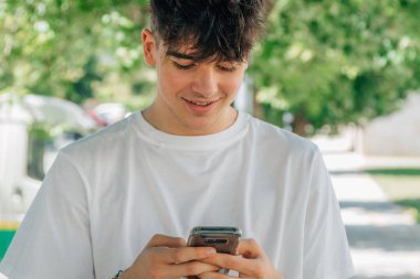 Sokakta cep telefonu olan genç bir çocuk.