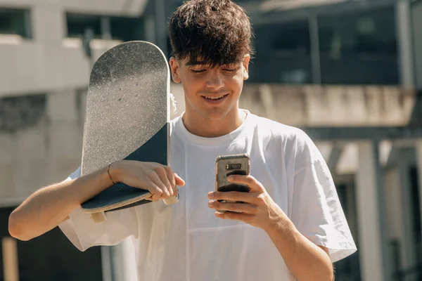 在街上带着手机和滑板的青少年 — 图库照片