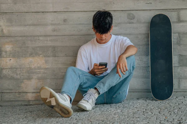 Tiener Jongen Met Mobiele Telefoon Skateboard Muur — Stockfoto