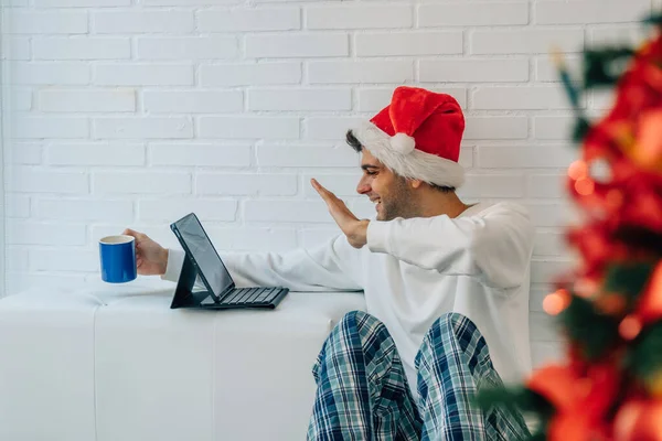 オンラインコンピュータビデオ会議でサンタの帽子をかぶったクリスマスのための家の男 — ストック写真