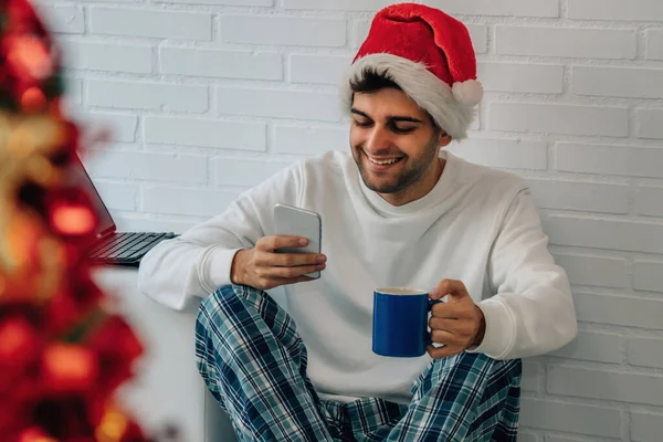 クリスマスに携帯電話とパソコンを持って家にいる男は — ストック写真