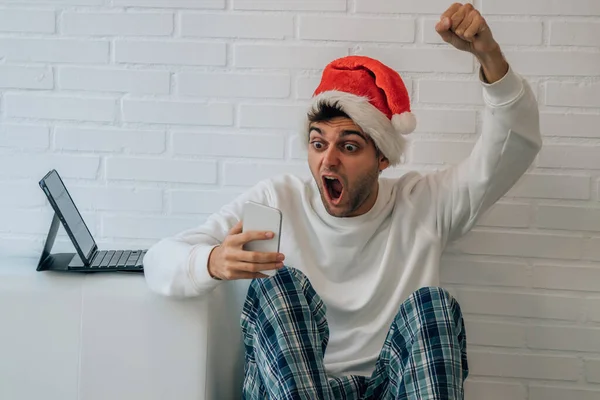 携帯電話と驚きの表情でクリスマスの家の男 — ストック写真
