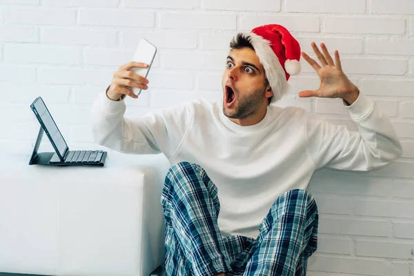 男人在家里过圣诞节 带着手机和惊讶的表情 — 图库照片