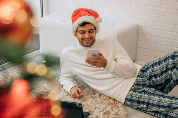 サンタ クラスの帽子を被った男とコンピュータと携帯電話 — ストック写真