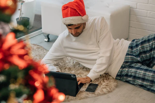 Homem Casa Natal Com Chapéu Papai Noel Com Computador Telefone — Fotografia de Stock