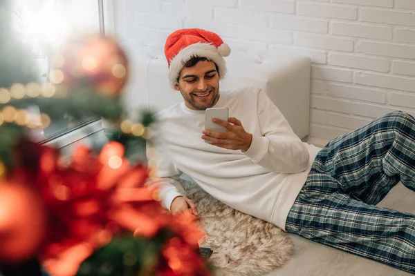 Man Thuis Kerst Met Kerstman Hoed Met Computer Mobiele Telefoon — Stockfoto